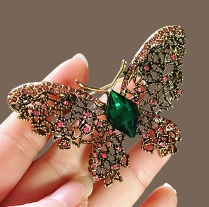 Élégante broche papillon avec strass roses et pierre verte sur socle en métal doré