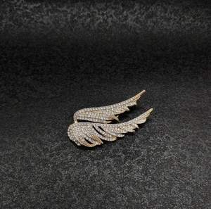 Detailed view of vintage gold wing brooch with pavé crystal rhinestones and fine feathers