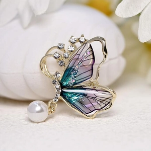 Élégante broche papillon avec ailes dégradées bleues, strass brillants et perle blanche