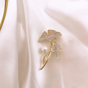 Detailed macro of golden ginkgo leaf brooch with crystals and a white pearl detail