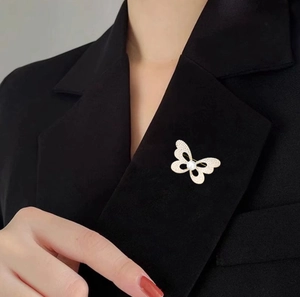 Vue détaillée d'une élégante broche papillon dorée avec cristaux blancs et perle centrale