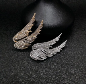 Close-up of gold and silver wing brooches with sparkling rhinestones on black background