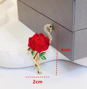 Détail broche flamant rose avec rose émaillée rouge et cristaux sur cadre doré