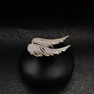 Sparkling crystal encrusted wing brooches in gold finish on professional black pedestal