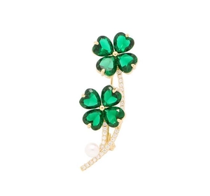 Detailed view of golden clover brooch with green crystal leaves and hanging pearl