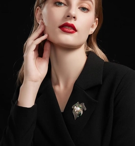 Gros plan détaillé d'une broche fleurie en perles et gemmes vertes sur un blazer noir