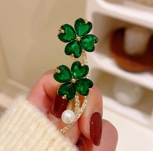Elegant gold four-leaf clover brooch with green crystals and a round white pearl charm