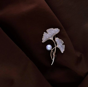 Detailed close-up of ginkgo leaf brooch with sparkling zircons and a white pearl accent