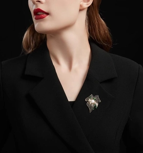 Détail d'une luxueuse broche fleur en perle avec feuilles vertes sur revers