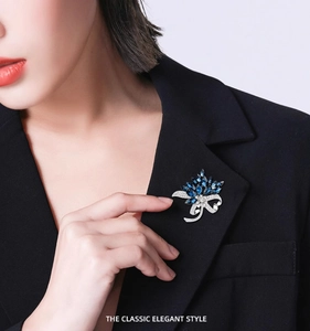 Detail of blue crystal bouquet brooch with silver bow on a black blazer lapel