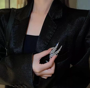 Close-up of sparkling silver wing brooches with rhinestones on a black blazer jacket