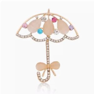 Broche parapluie dorée élégante avec pierres œil de chat et cristaux colorés sur blanc