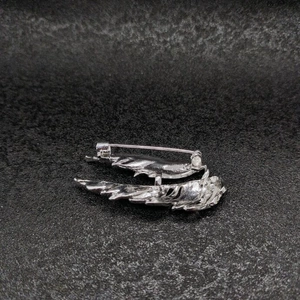 Detail view of the silver wing brooch back showing the secure safety pin fastening mechanism