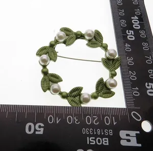 Detail of a round vintage green leaf brooch with pearls, measuring 5.5cm in diameter