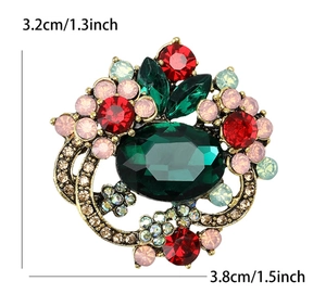 Detail shot showing a crystal flower brooch with emerald gem and dimensions 3.2cm by 3.8cm