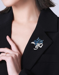 Detailed close-up of a vintage bouquet brooch with blue gems on a black suit lapel