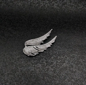 Detailed close-up of silver wing brooch pins with sparkling pavé-set rhinestones