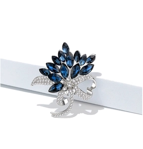 Macro view of vintage blue crystal flower brooch with silver ribbon and pavé diamonds