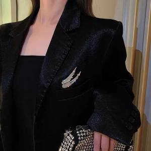 Macro shot of luxury wing brooch with white crystals on a black textured blazer lapel