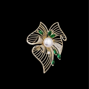 Broche fleur dorée luxueuse avec une grande perle blanche et gemmes vertes