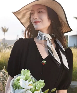 Détail de la broche fraise rouge avec fleur blanche épinglée sur une robe noire élégante