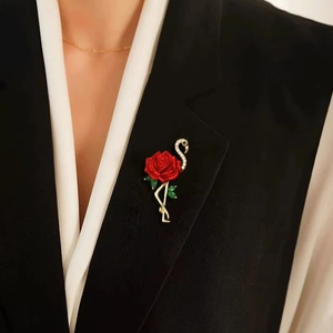 Broche flamant rose et fleur rouge avec strass blancs sur le revers d'un tailleur noir