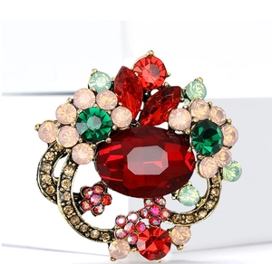 Detail view of a vintage floral brooch with red emerald crystals on antique gold metal