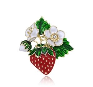 Vue détaillée d'une broche fraise de luxe avec émail rouge et petites fleurs blanches