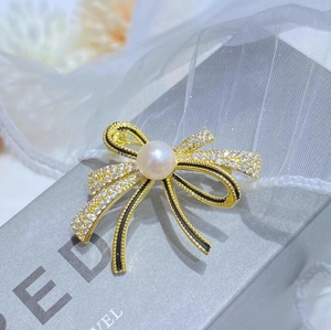 Elegant gold bow brooch with sparkling crystals, black enamel and a center white pearl