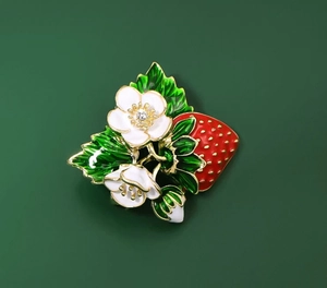 Détail de la broche fraise en émail rouge avec finitions dorées et fleurs