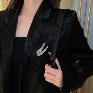 Macro shot of silver wing brooch with clear pavé crystals on a black blazer lapel