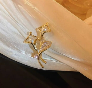 Detailansicht der Lilienbrosche mit weißen Perlen und Zirkonia-Besatz auf weißer Seide