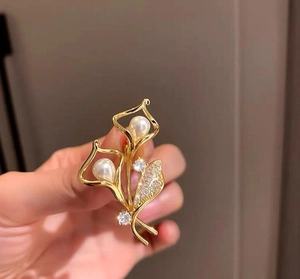 Detailansicht der goldenen Lilien-Brosche mit zwei Perlen und funkelnden Zirkonia-Steinen