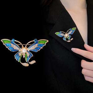 Squisita spilla a farfalla dorata con smalto blu e strass sul risvolto della giacca