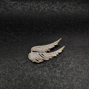 Exquisite golden wing brooch with full crystal paving on a minimalist black background