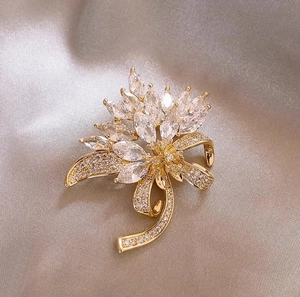 Detailed view of maple leaf brooch with sparkling zircons on elegant champagne silk fabric