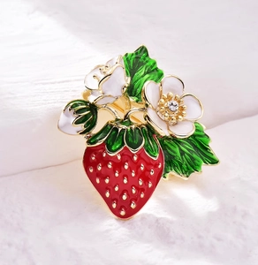 Détail de la broche fraise de luxe avec fleurs en émail blanc et base en alliage doré