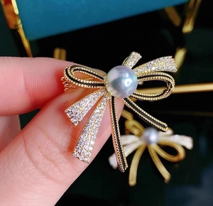 Macro shot of ribbon bow brooch with white pearl inlay and sparkling diamond accents