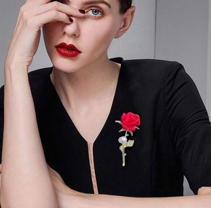 Detailed view of elegant red rose brooch with pearl and sparkling zircon on black clothing