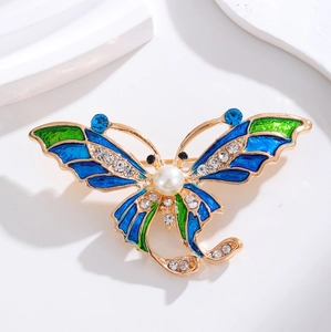 Elegante spilla a farfalla in oro con smalto blu, perla bianca e strass luccicanti