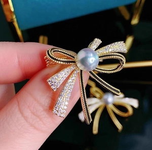 Macro shot of a ribbon bow brooch with micro-pave crystals and a central pearl accent