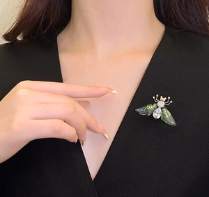 Detailed close-up of a sparkling crystal bee brooch on a black fabric garment