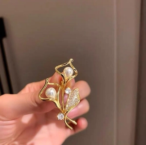 Detail einer Lilien-Brosche mit weißen Perlen und Zirkoniasteinen auf Vergoldung