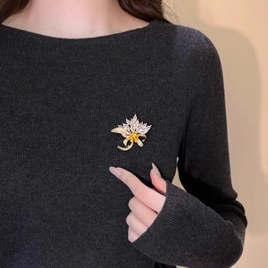 Elegant maple leaf brooch with sparkling crystals on a gray knit sweater