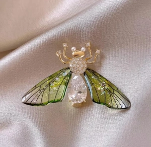 Elegant gold bee brooch with green translucent wings and teardrop crystal on silk