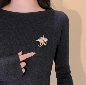 Elegant gold maple leaf brooch with sparkling crystals on black knitwear garment