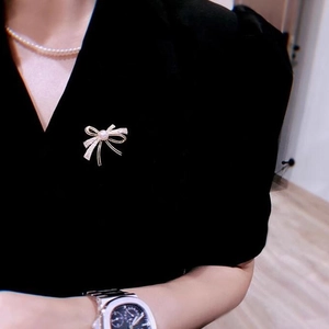 Elegant gold bow brooch with white pearls and sparkling rhinestones on black suit