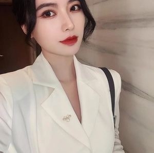 Detailed view of an elegant bee-shaped brooch with pearl accent on a white blazer lapel