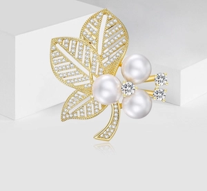 Detailansicht der eleganten Blattbrosche in Gold mit weißen Perlen und Zirkoniasteinen