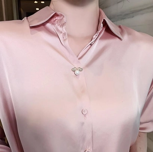 Close-up of elegant bee-shaped pearl brooch pin on light pink satin silk blouse